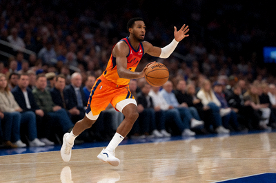 NBA比赛中球员突破上篮的瞬间，球场灯光明亮，观众席背景虚化